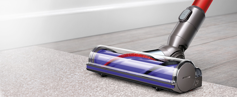 Close up of the Dyson V6 Cord-free vaccuum's motorised brush bar being used to collect hair and ground dirt from a carpet.