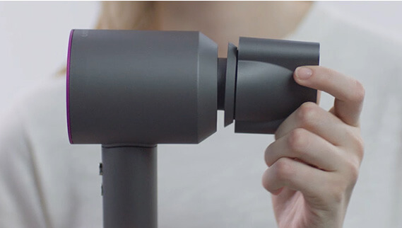 Woman clipping an attachment to her Dyson Supersonic™ hair dryer