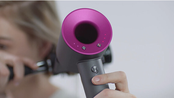 Woman pressing the Dyson Supersonic™ hair dryer Cold shot button to set her style
